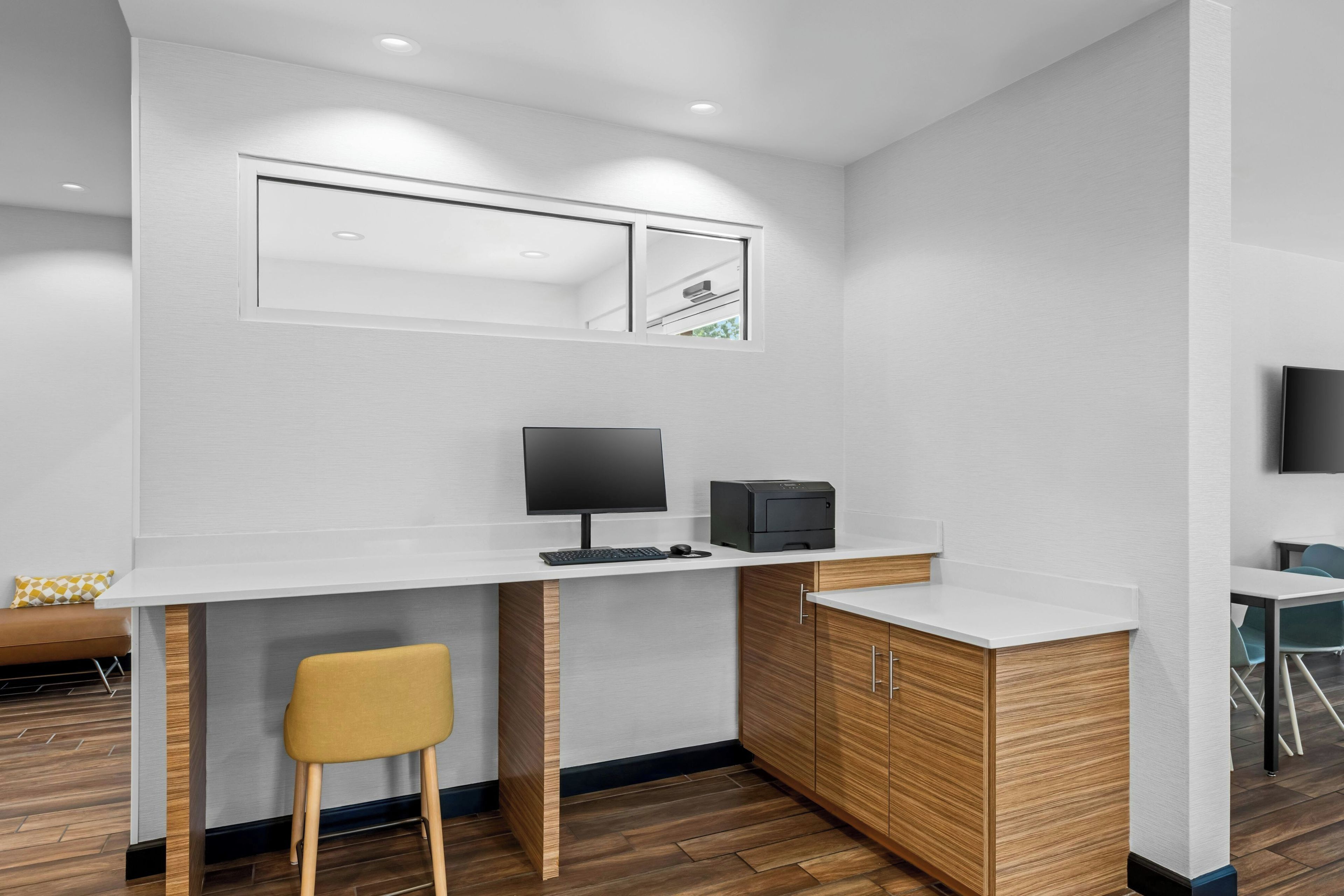 Een moderne kantoorruimte met een wit bureau, een computer, een printer en een stoel.