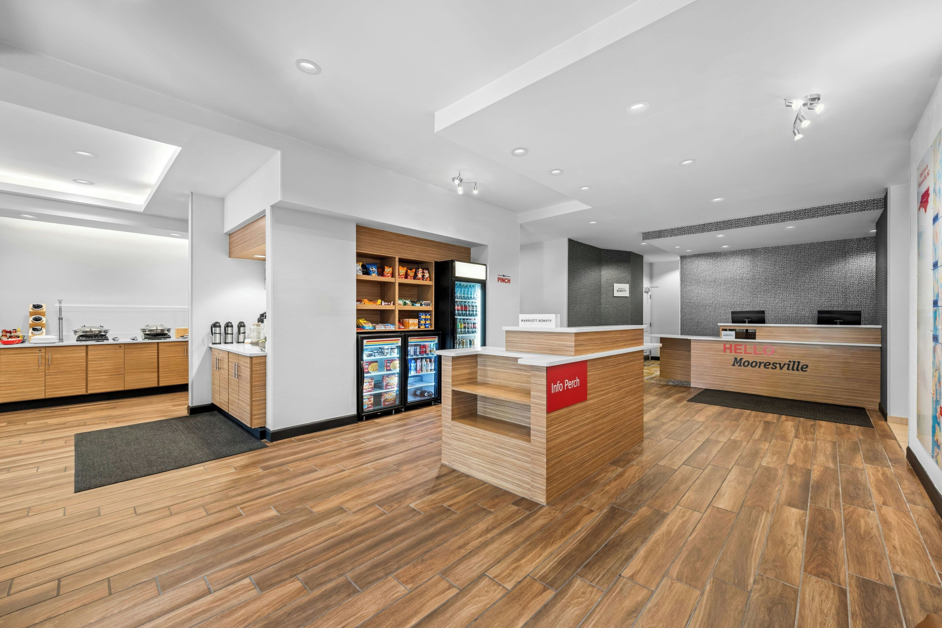 A modern hotel lobby with a reception desk, a minibar, and a seating area.