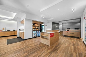 Un moderno vestíbulo de hotel con una recepción, un minibar y una zona de estar.