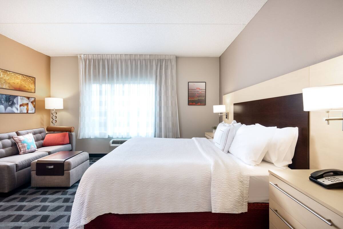 Een hotelkamer met een groot bed, een bank, een bureau en een nachtkastje.