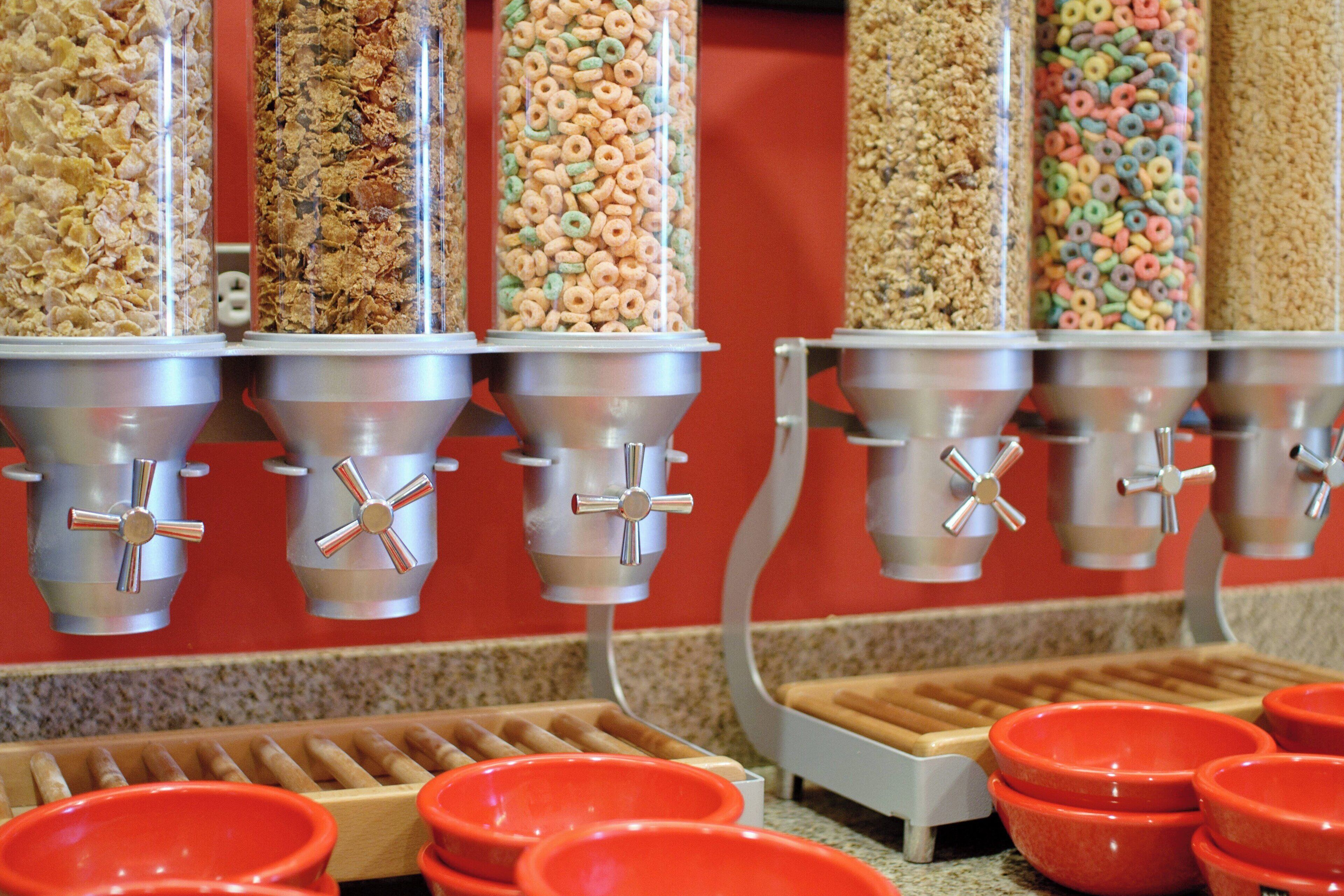 A cereal dispensing machine with multiple dispensers and red bowls.