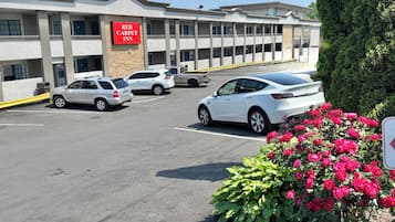 Un Hotel Red Carpet con aparcamiento, varios coches y una fila de balcones.