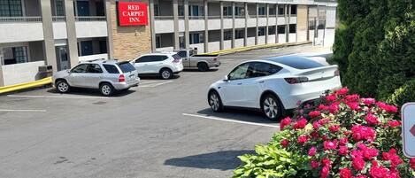 Un Hotel Red Carpet con aparcamiento, varios coches y una fila de balcones.