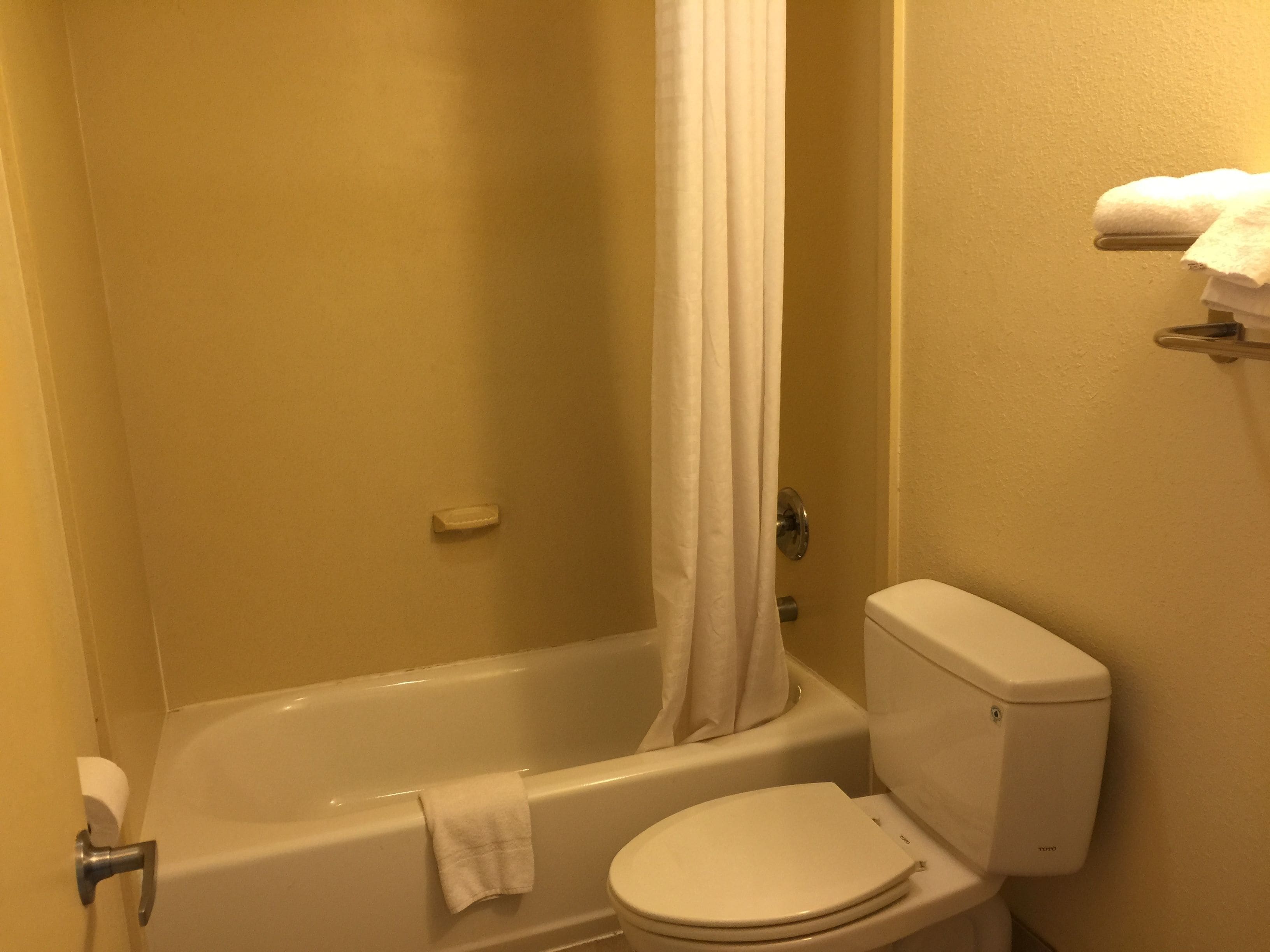 A bathroom with a bathtub, toilet, and a shower curtain.