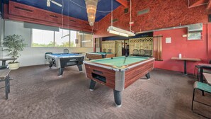 A pool hall with multiple pool tables, ceiling fans, and a chandelier. - Red Carpet Inn (Stamford)