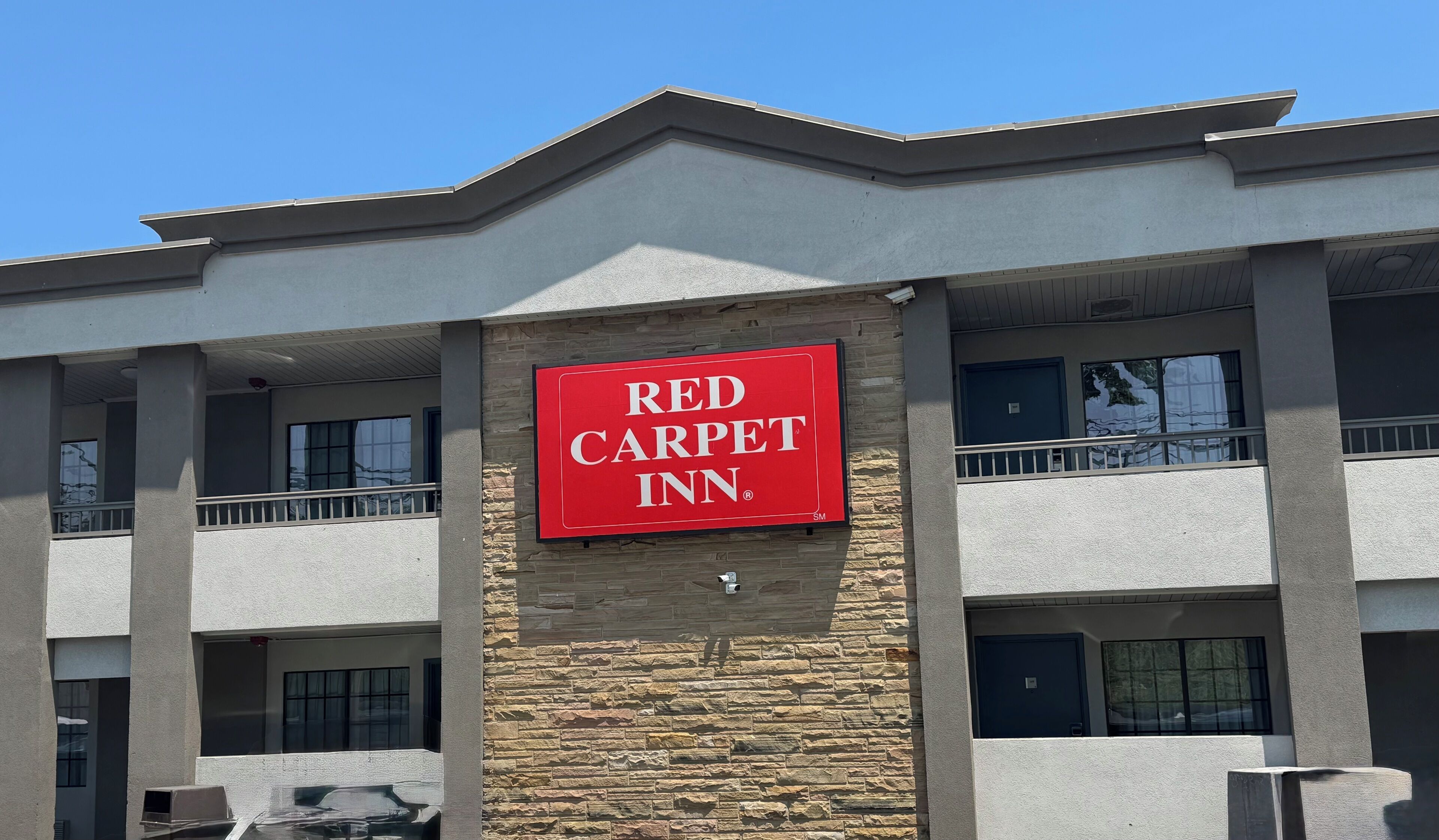 Un bâtiment de la chaîne Red Carpet Inn, doté d’une façade en pierre et de plusieurs balcons.