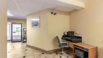 A reception area with a desk, computer, chair, and a small wooden cabinet.
