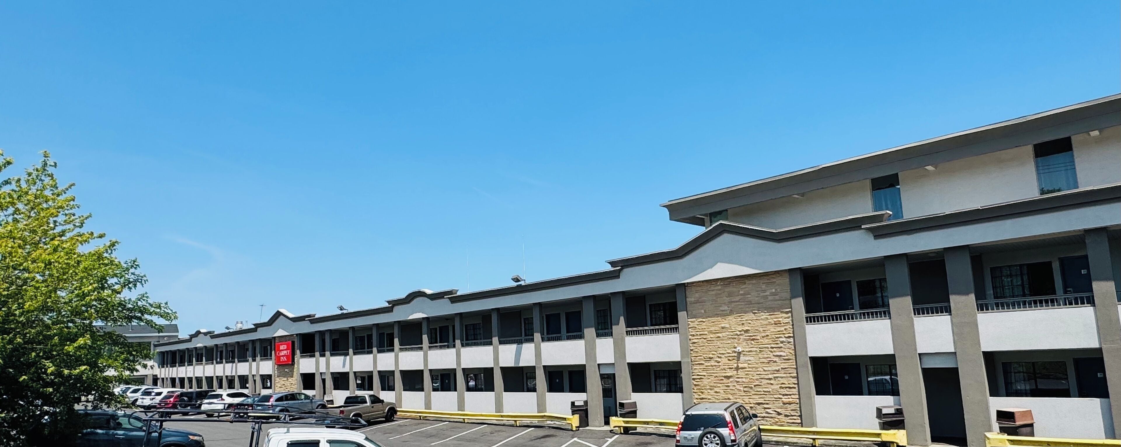 A multi-story hotel with a modern design, featuring a parking lot with several cars.