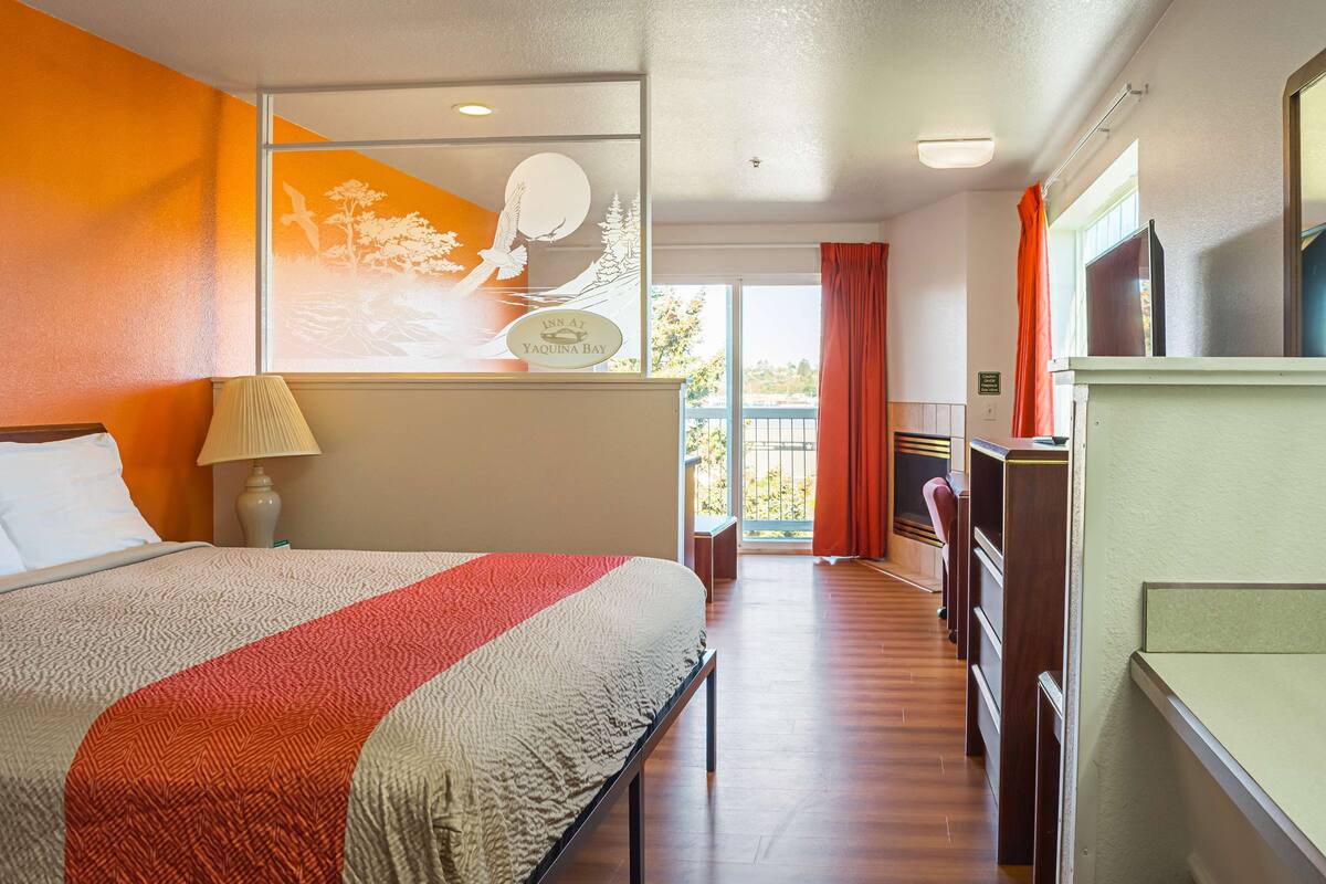 Ein Hotelzimmer mit Bett, Schreibtisch, Fernseher und Blick ins Freie.