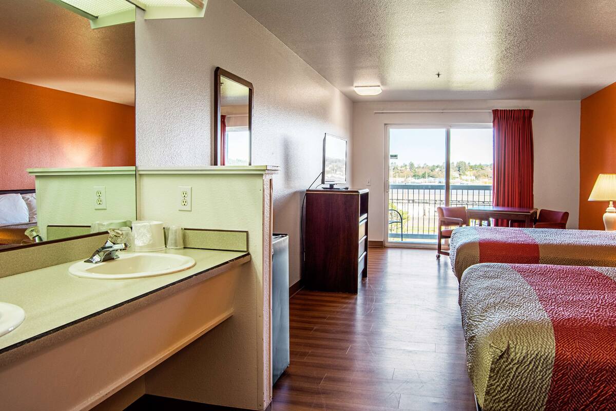Ein Hotelzimmer mit Bad, Schreibtisch, Stuhl und Bett.