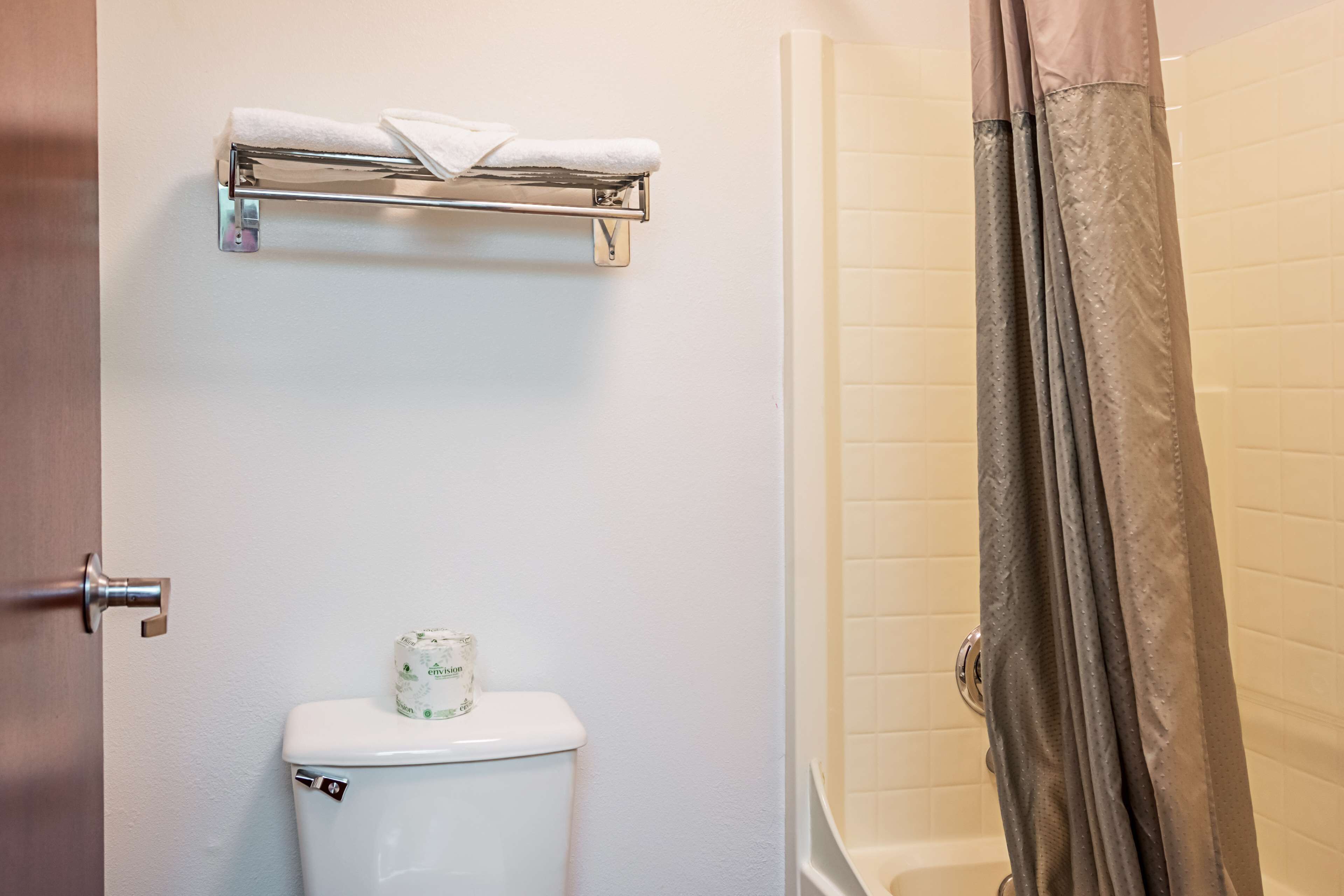 A bathroom with a toilet, a towel rack, and a shower curtain.
