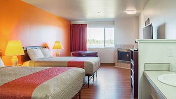 A hotel room with two beds, a TV, a fireplace, and a window with a view.