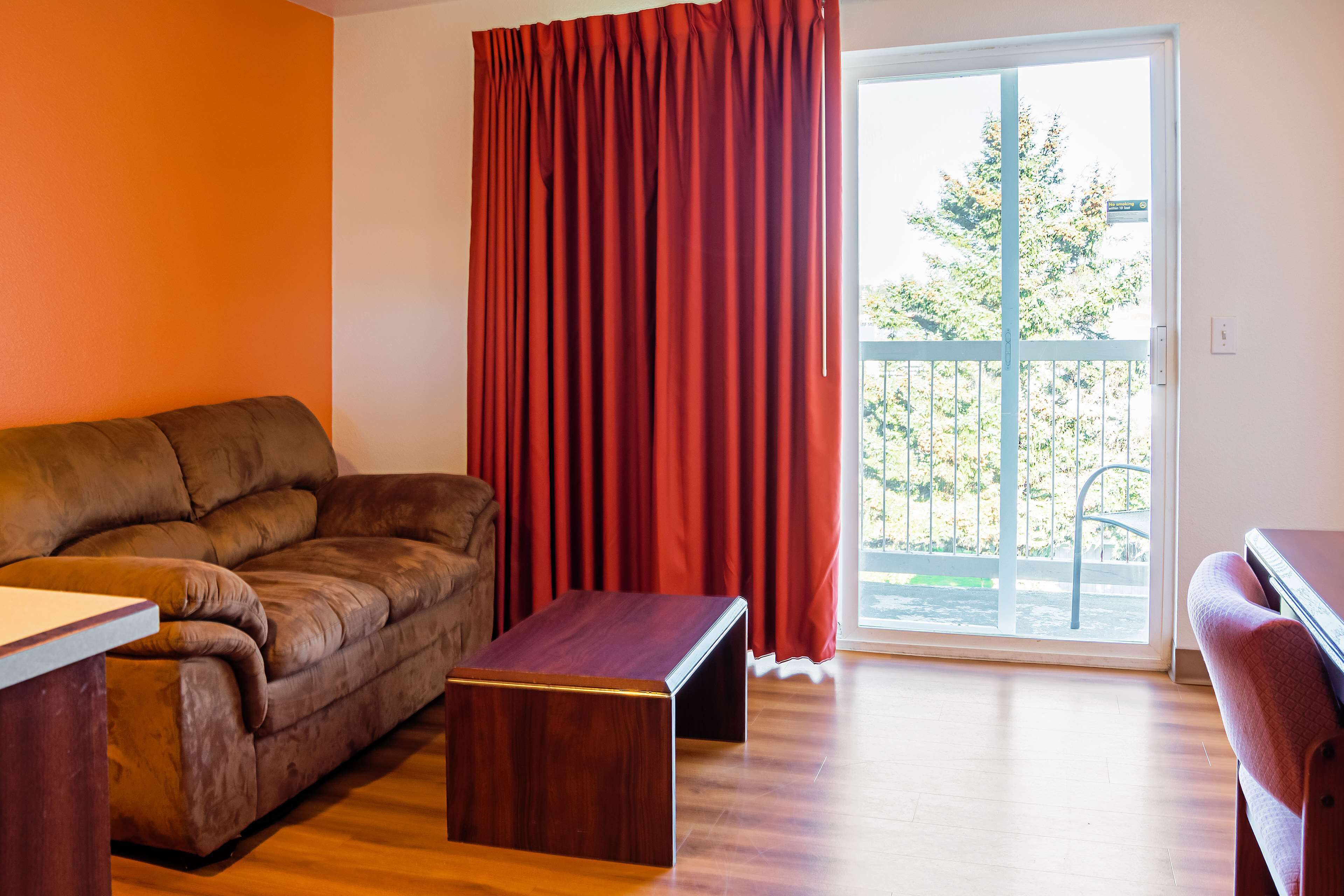A living room with a brown leather sofa, a wooden coffee table, and a sliding glass door leading to an outdoor area.