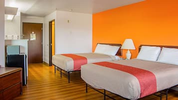 Une chambre d’hôtel avec deux lits, un plancher en bois, un bureau et une salle de bain visible au fond.