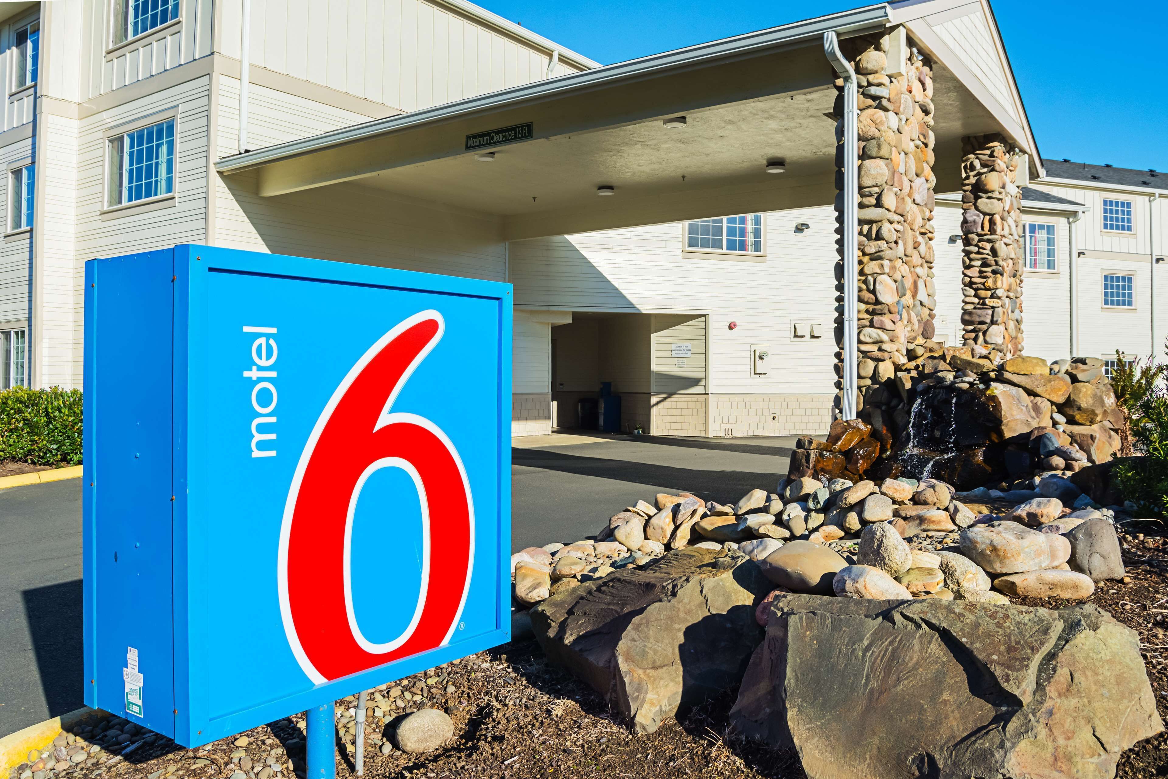 Une enseigne de motel avec le chiffre 6, un pilier en pierre et l’entrée d’un bâtiment.