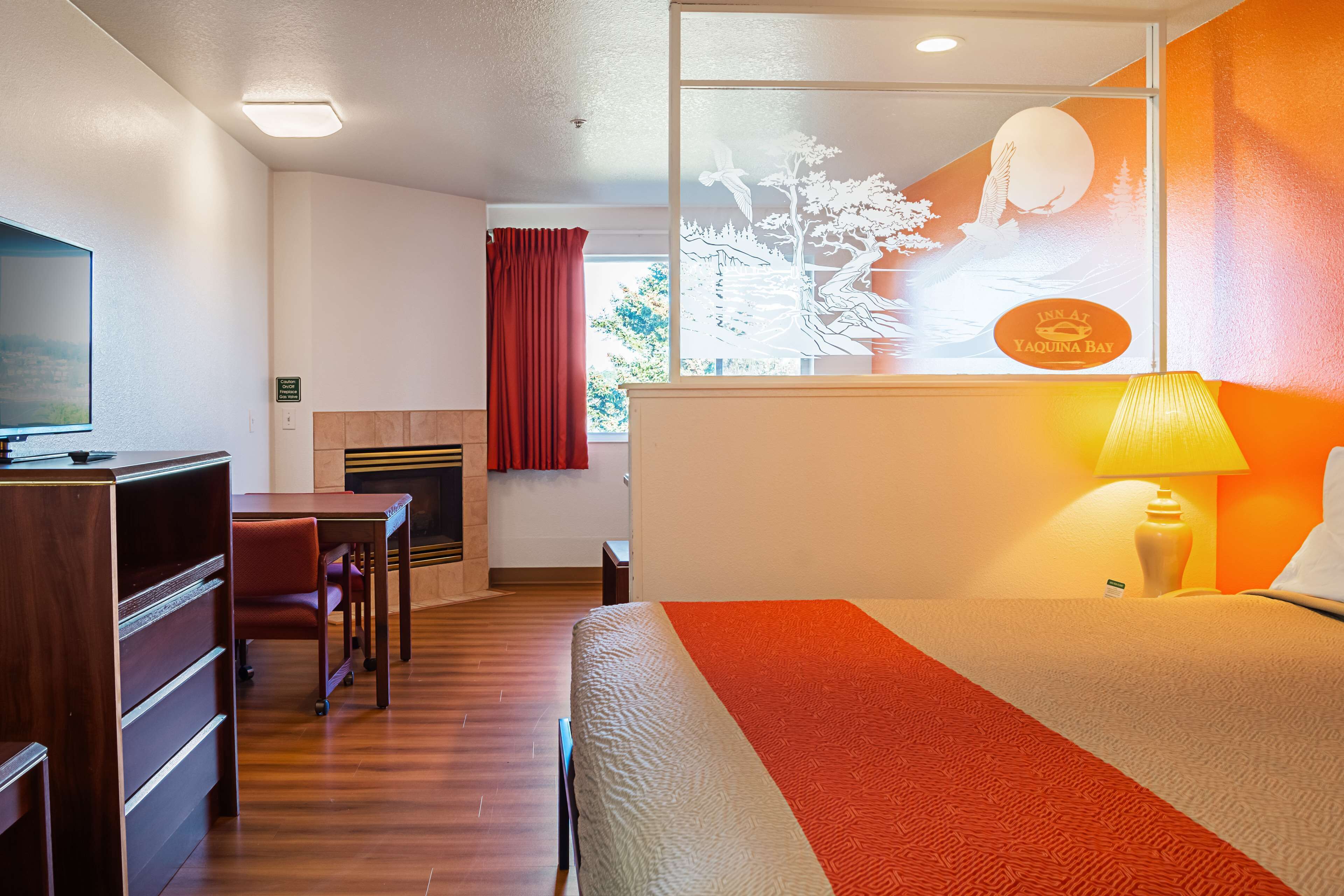 A hotel room with a bed, desk, chair, and a television.