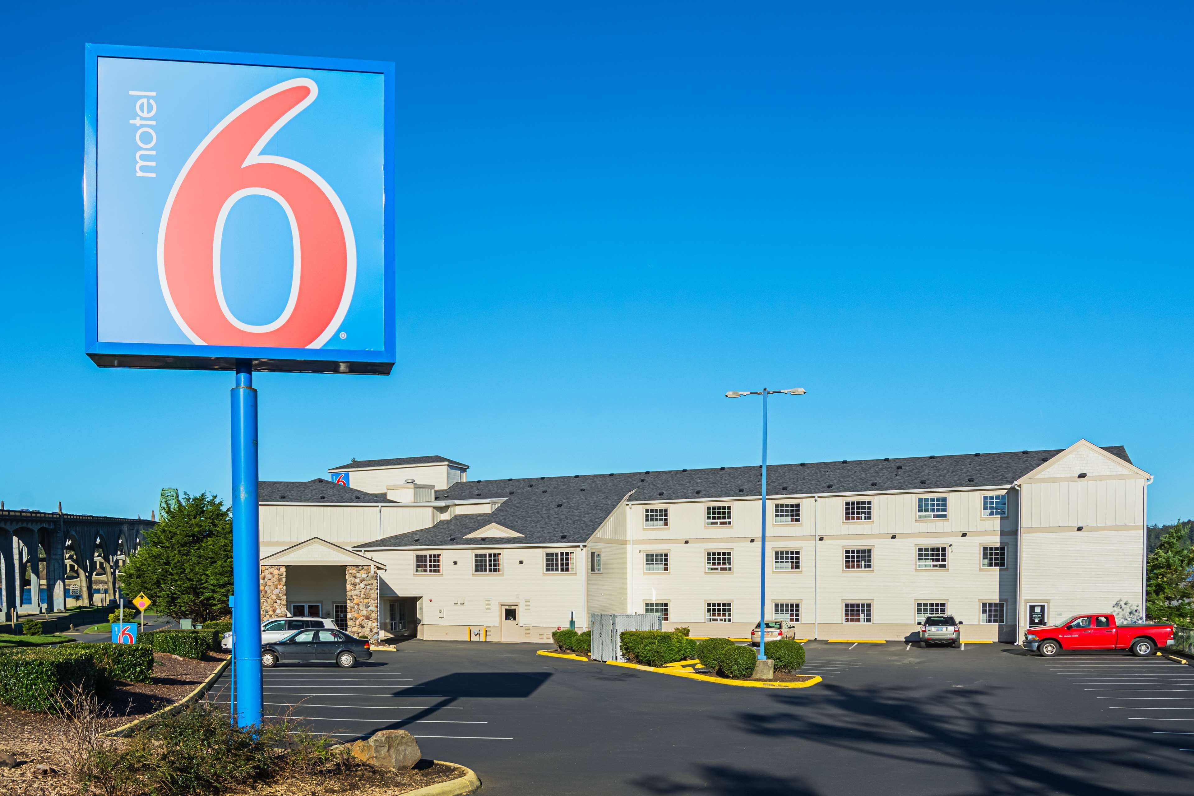 Un letrero de motel, un estacionamiento y un edificio con varias ventanas y techo plano.
