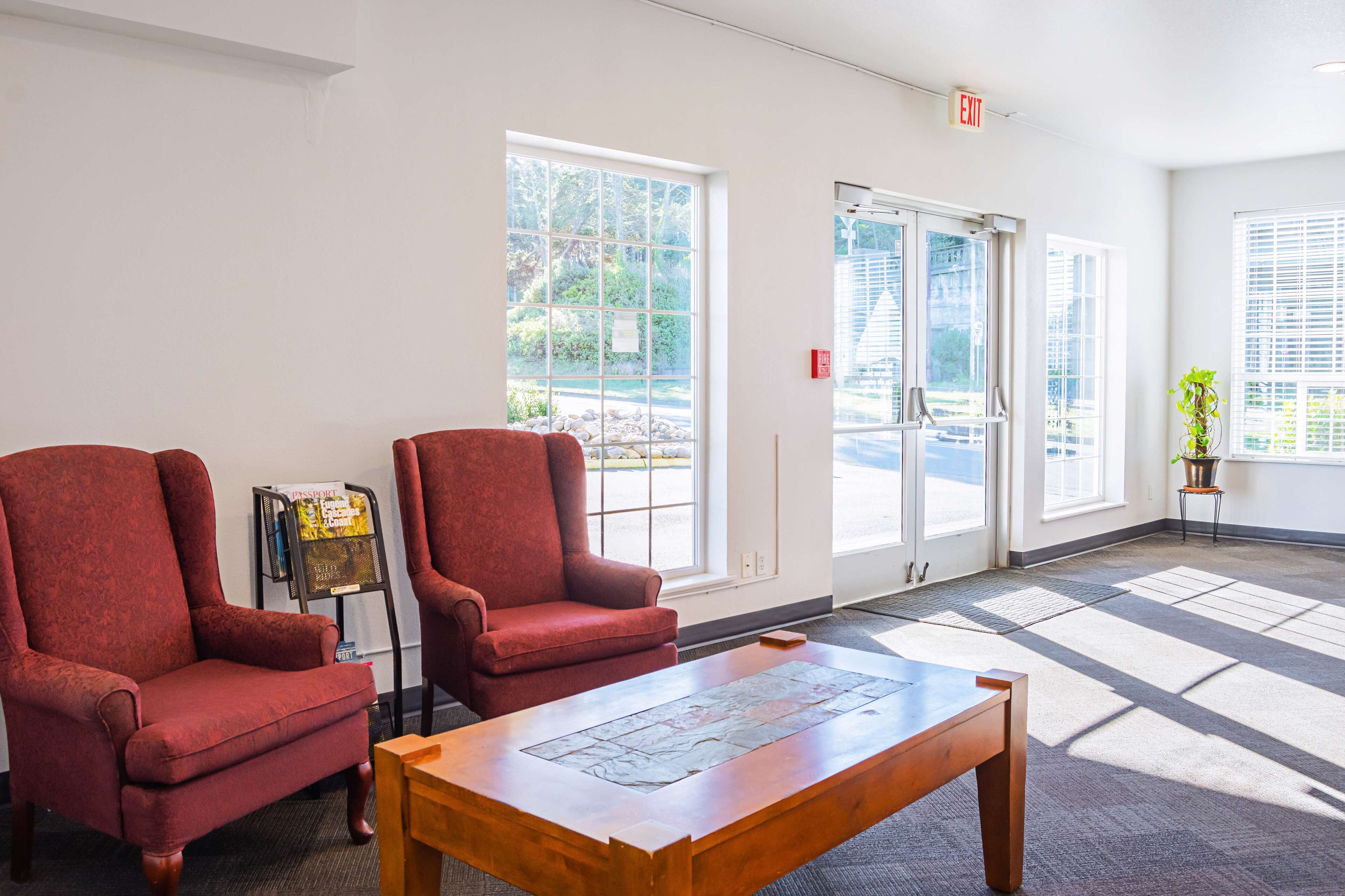 A lobby with two red armchairs, a wooden coffee table, and a magazine rack.