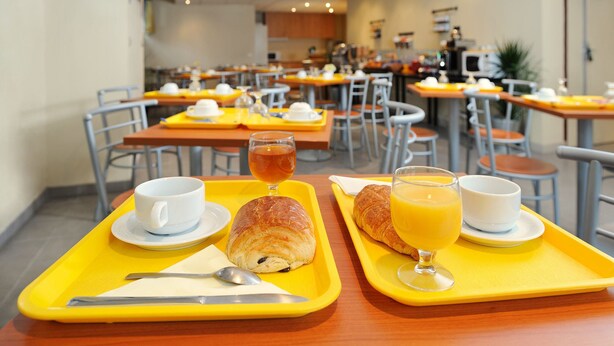 Desayuno con bandejas que incluyen croissants, jugo y tazas de café.