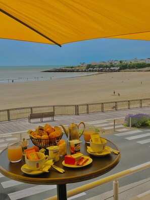 A table with breakfast items and a view of the beach. - The Originals Boutique, Hôtel Miramar (Royan)