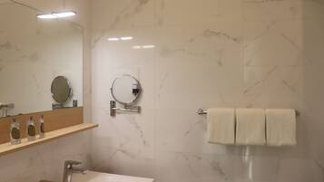 Une salle de bain moderne avec un mur en marbre, un lavabo avec un miroir et un porte-serviettes.
