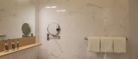 Un baño moderno con pared de mármol, un lavabo con espejo y un perchero para toallas.