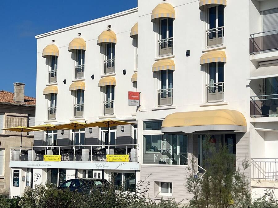Ein modernes Hotel mit mehreren Balkonen, einem Café und einem Schild, das es als Hotel kennzeichnet.
