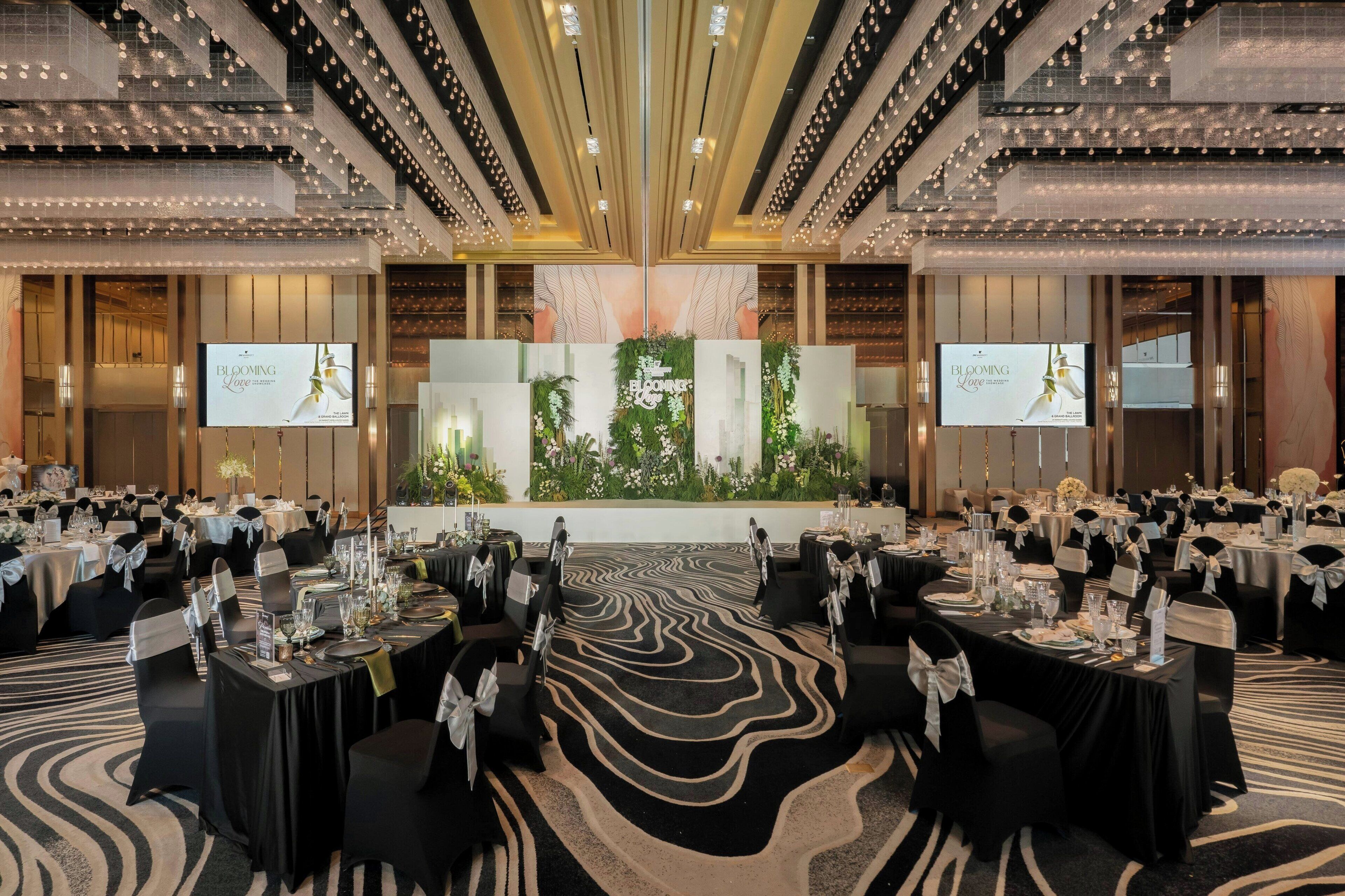 Une salle de banquet avec des tables rondes, des chaises noires et une scène centrale.