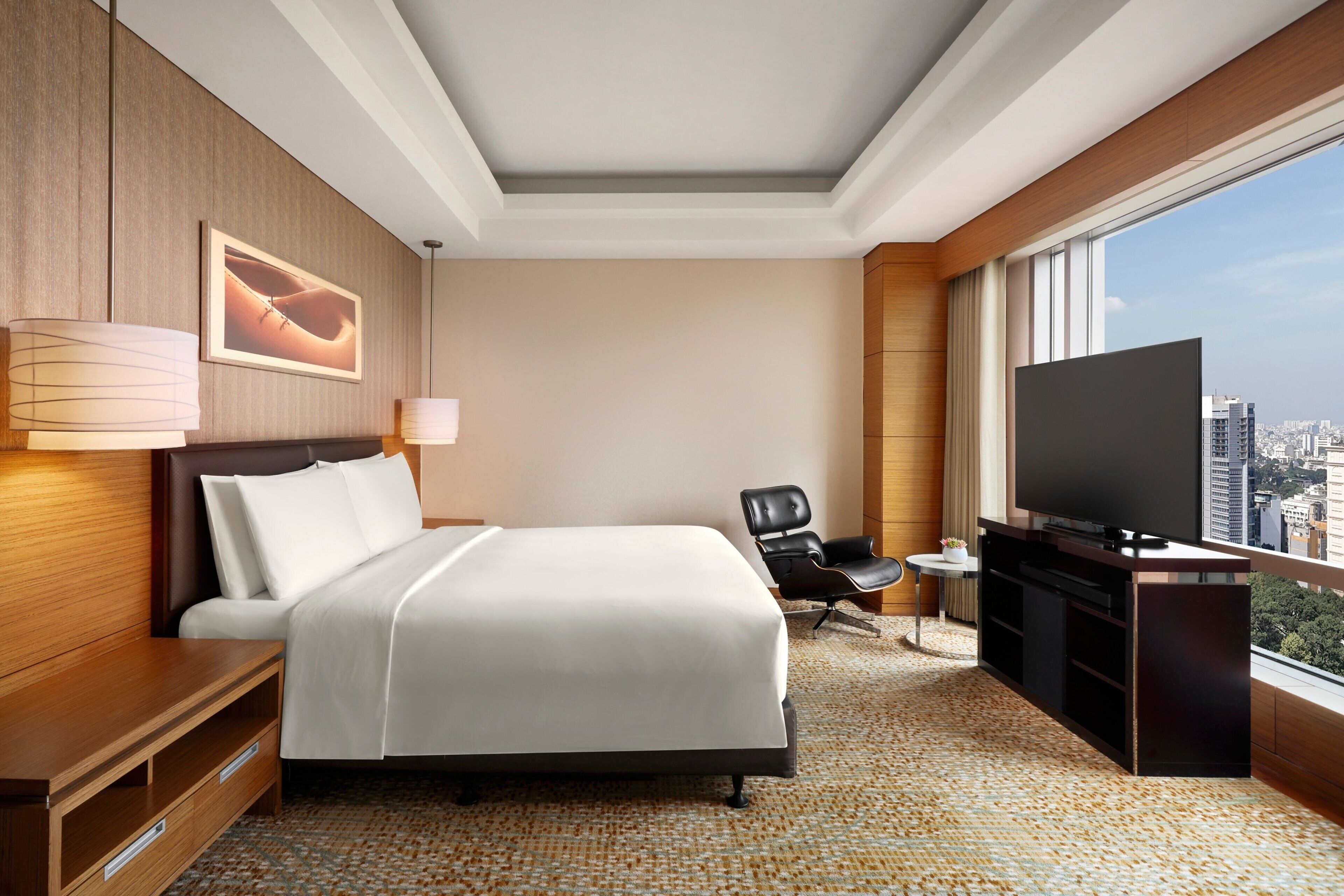 A hotel room with a large bed, a TV, a desk, and a chair.