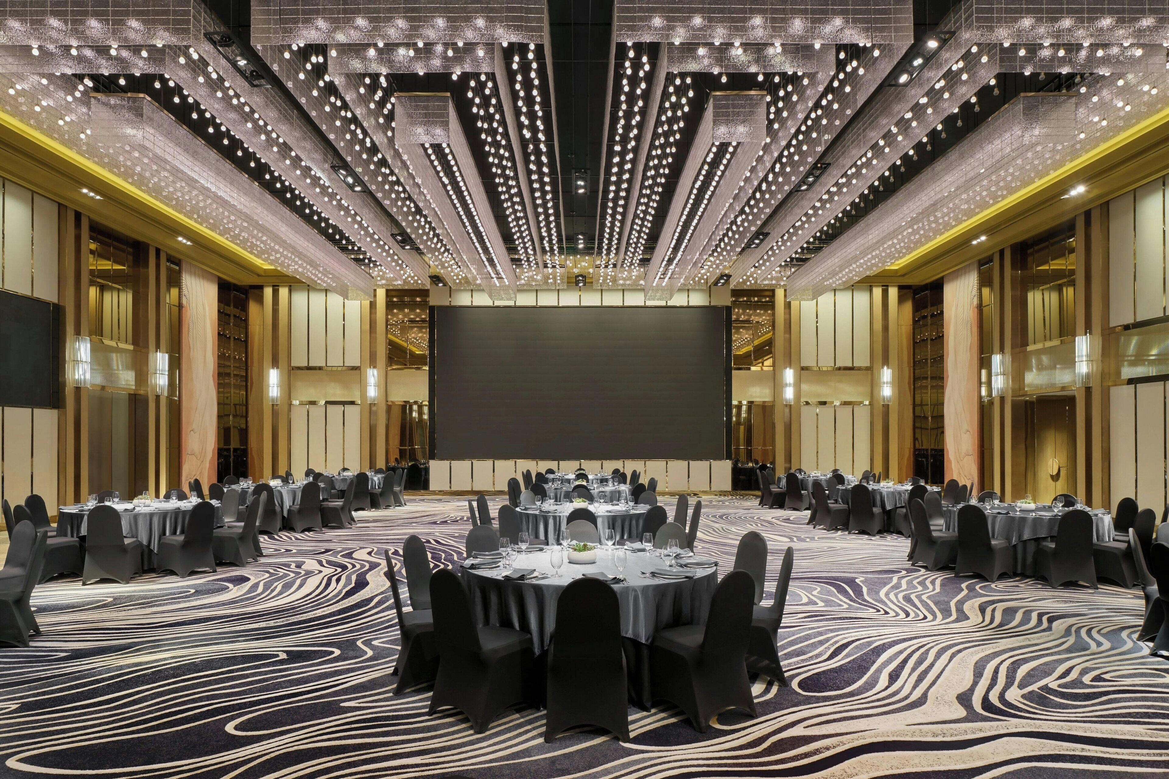 A large conference room with round tables, black chairs, and a patterned carpet.