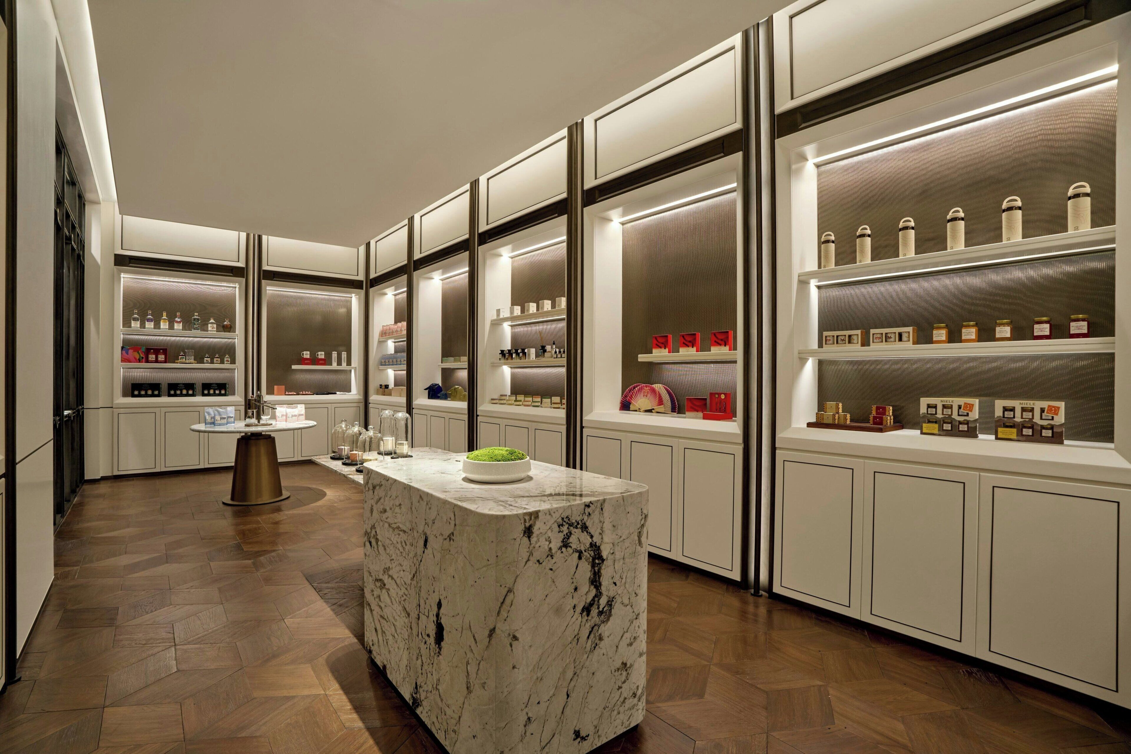 A modern kitchen with a marble island, built-in shelves with various items, and a herringbone wood floor.