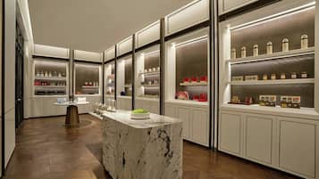 A modern kitchen with a marble island, built-in shelves with various items, and a herringbone wood floor.