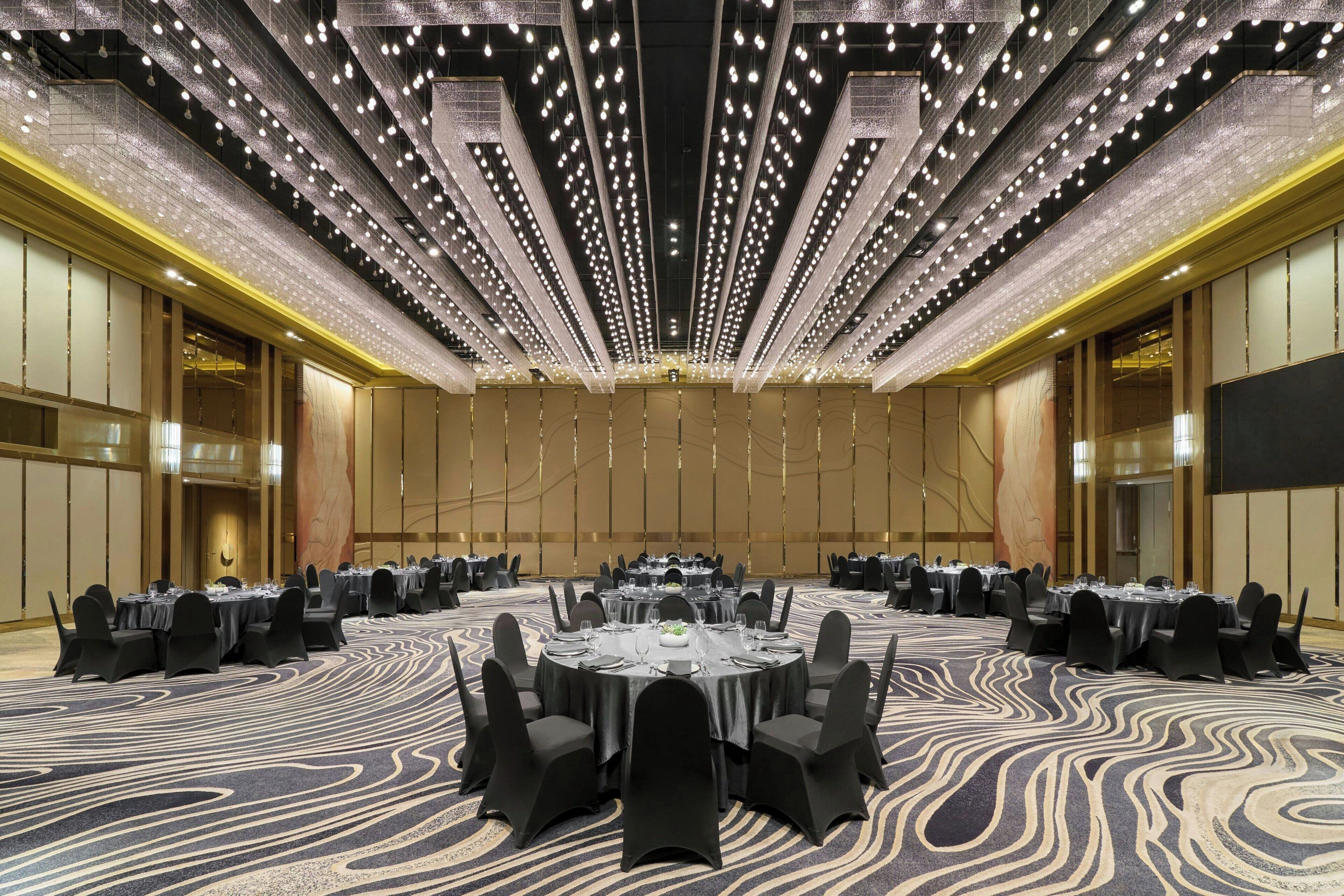 A conference room with round tables, black chairs, and a patterned carpet.