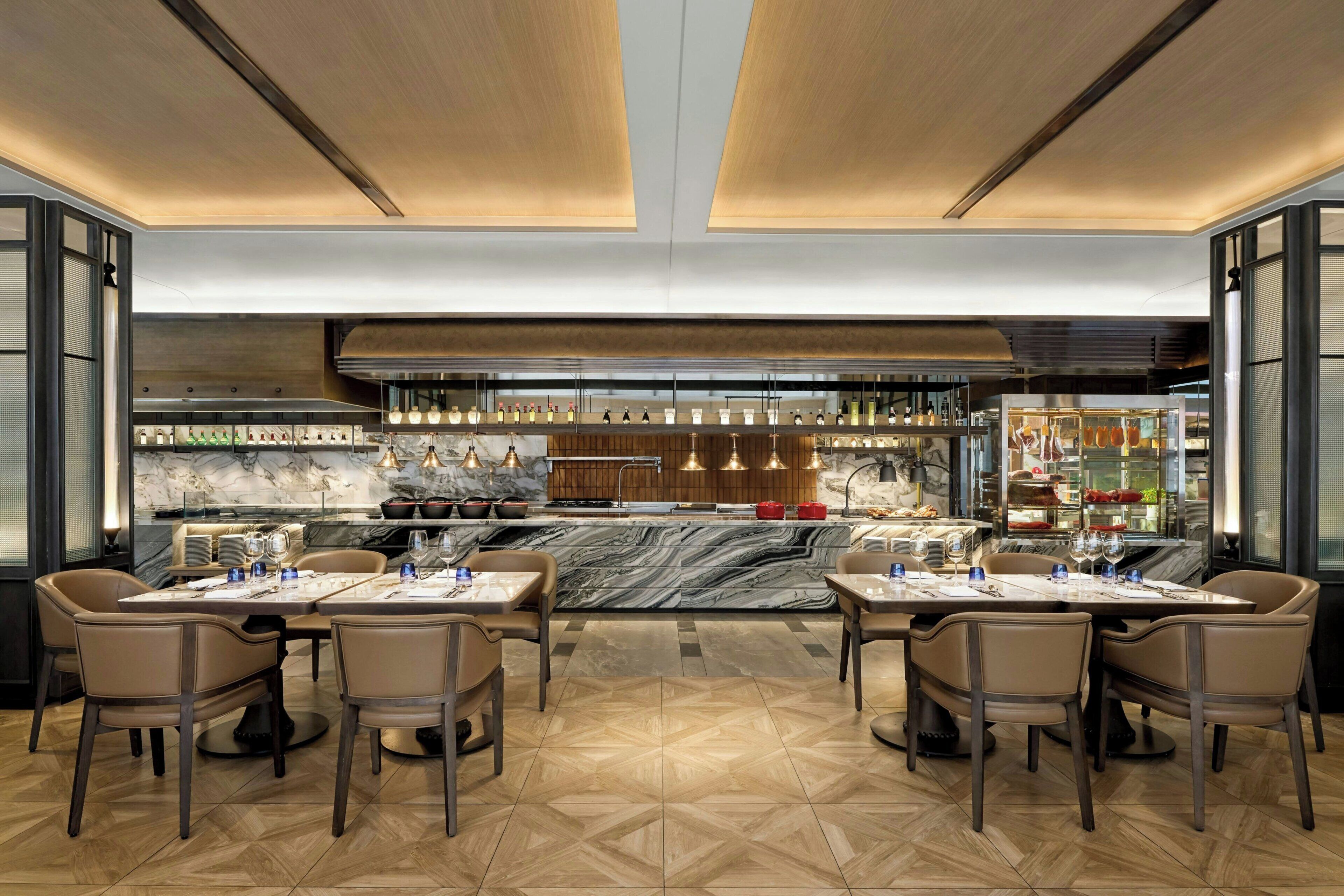 Un restaurant moderne doté d’un bar en marbre, d’un plafond en bois et d’un sol orné d’un motif en chevrons.
