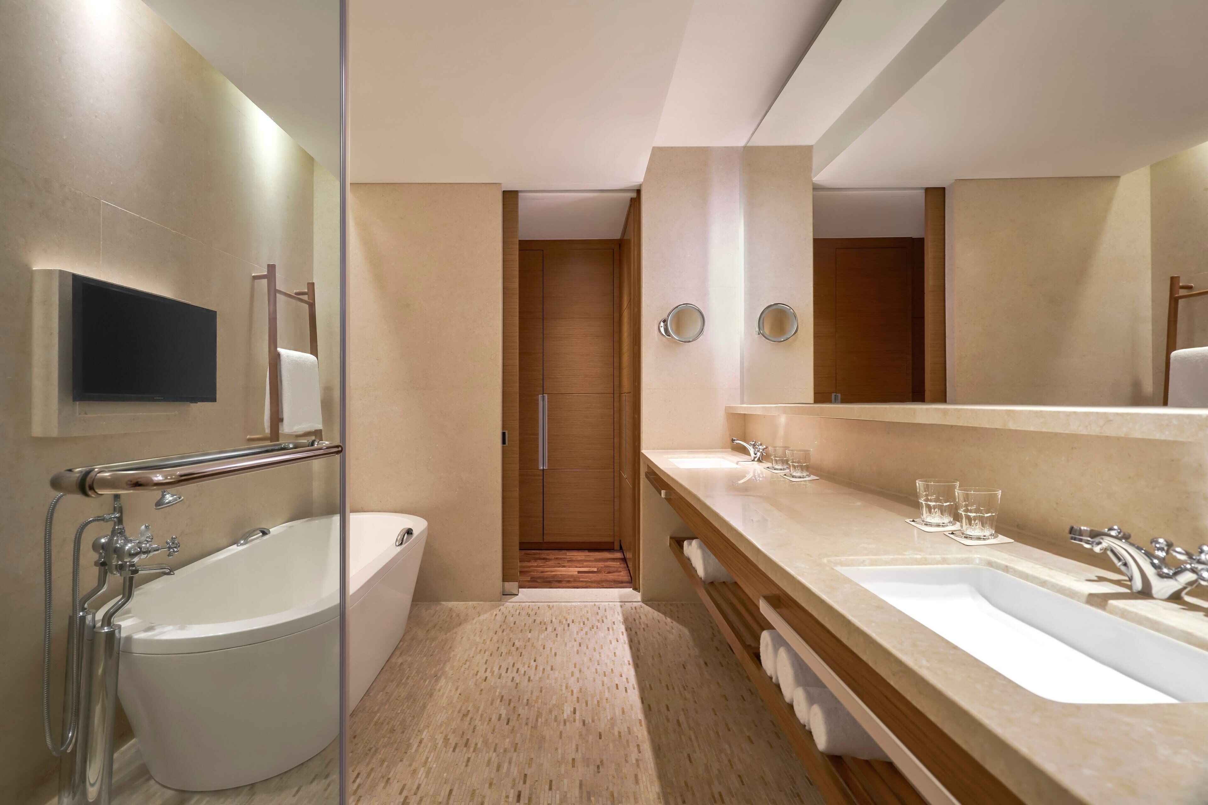 Een moderne badkamer met een bad, toilet en wastafelmeubel met een wastafel en spiegel.