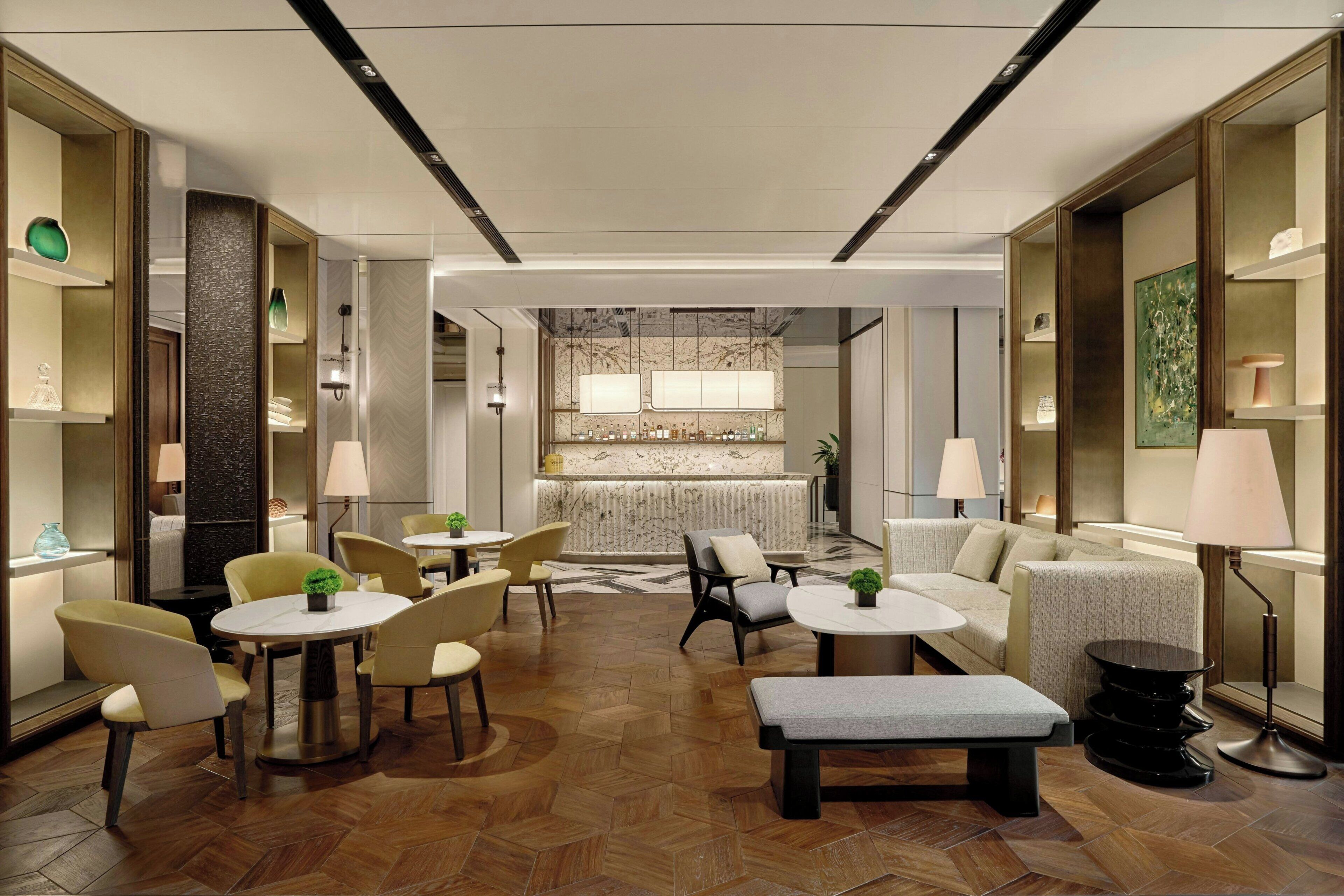 A modern hotel lobby with round tables, sofas, and a reception desk.