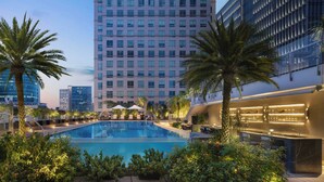 A rooftop pool with lounge chairs and palm trees, surrounded by modern buildings. - JW Marriott Hotel & Suites Saigon (Ho Chi Minh City)