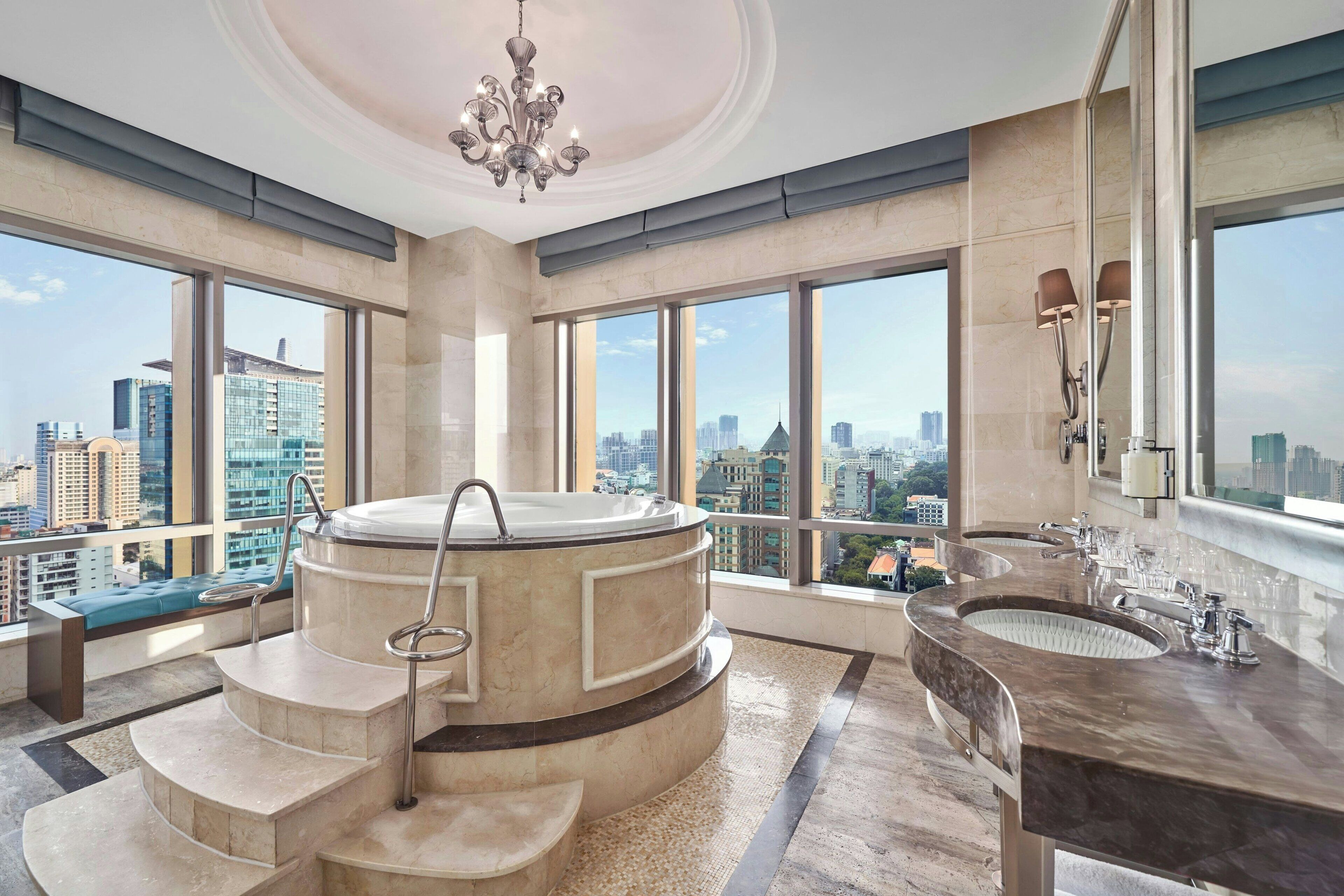 A luxurious bathroom with a large bathtub, a modern vanity, and large windows offering a city view.