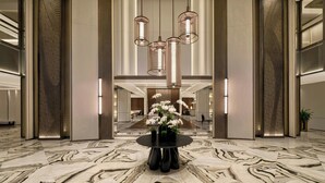 A spacious lobby with a marble floor, a round table with vases, and modern pendant lighting. - JW Marriott Hotel & Suites Saigon (Ho Chi Minh City)