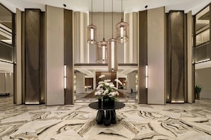A spacious lobby with a marble floor, a round table with vases, and modern pendant lighting. - JW Marriott Hotel & Suites Saigon (Ho Chi Minh City)