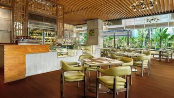 Un restaurante con techo de madera, paredes de vidrio y sillas verdes.