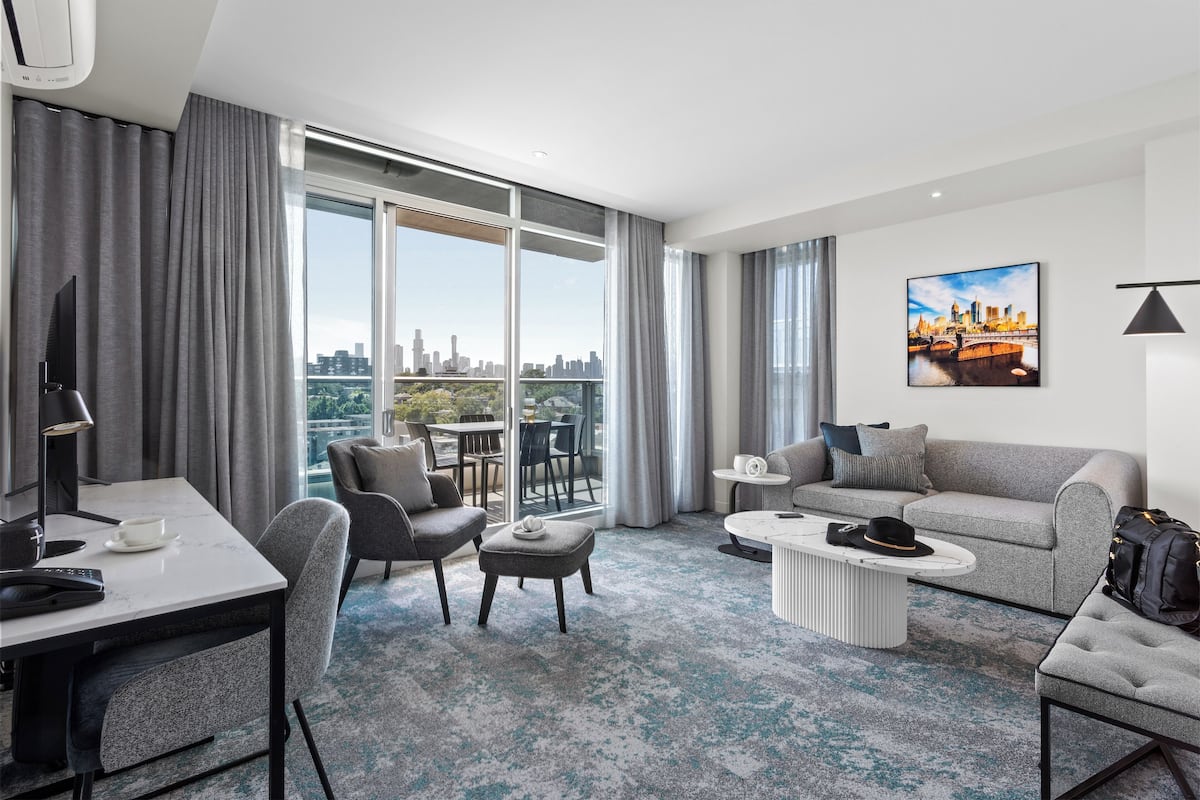 Et moderne hotelværelse med udsigt over byen, et spiseområde, en sofa og et sofabord.