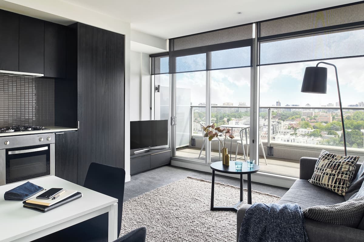 En moderne lejlighed med et køkken, spiseplads og en stor balkon med udsigt over byen.