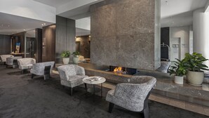 A modern lobby with a stone fireplace, seating area, and potted plants.