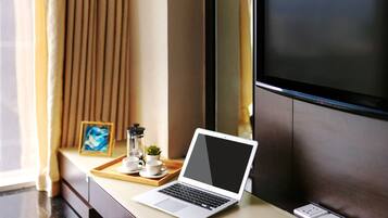 A laptop on a desk with a tray of cups and a small plant.