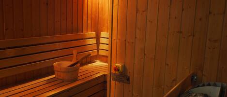 Un sauna en bois avec des bancs et un seau.