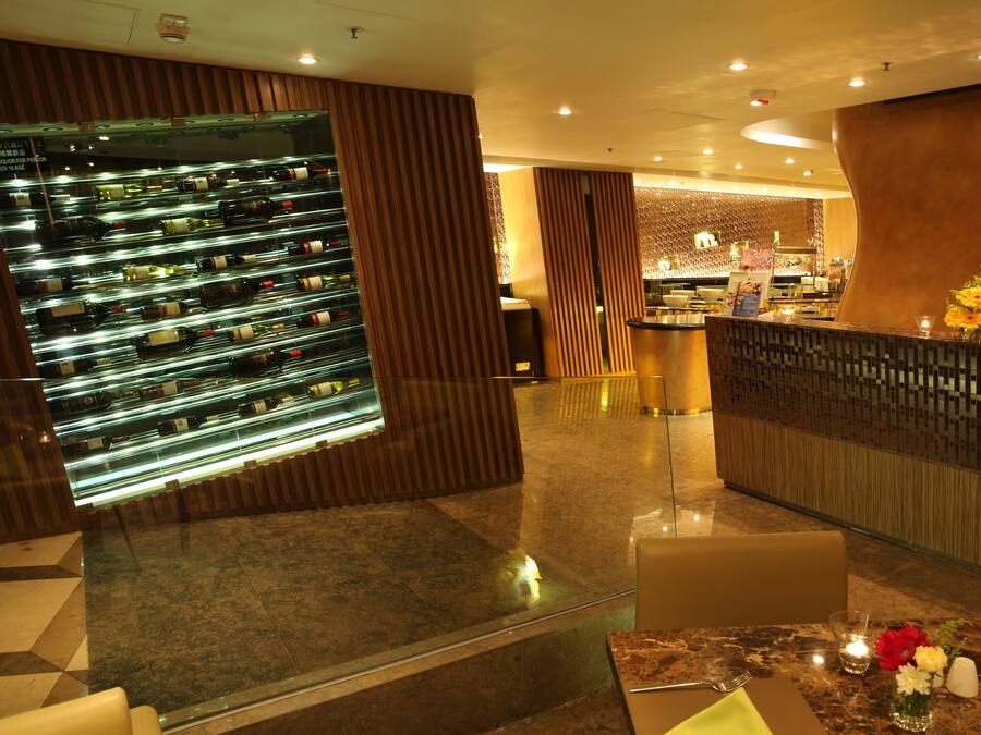 A modern hotel lobby with a wine display, a reception desk, and a seating area.