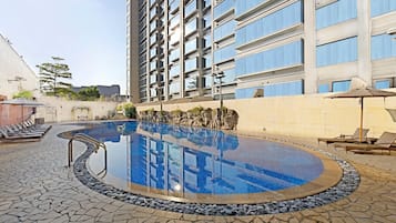 A swimming pool with lounge chairs and a stone-tiled deck.