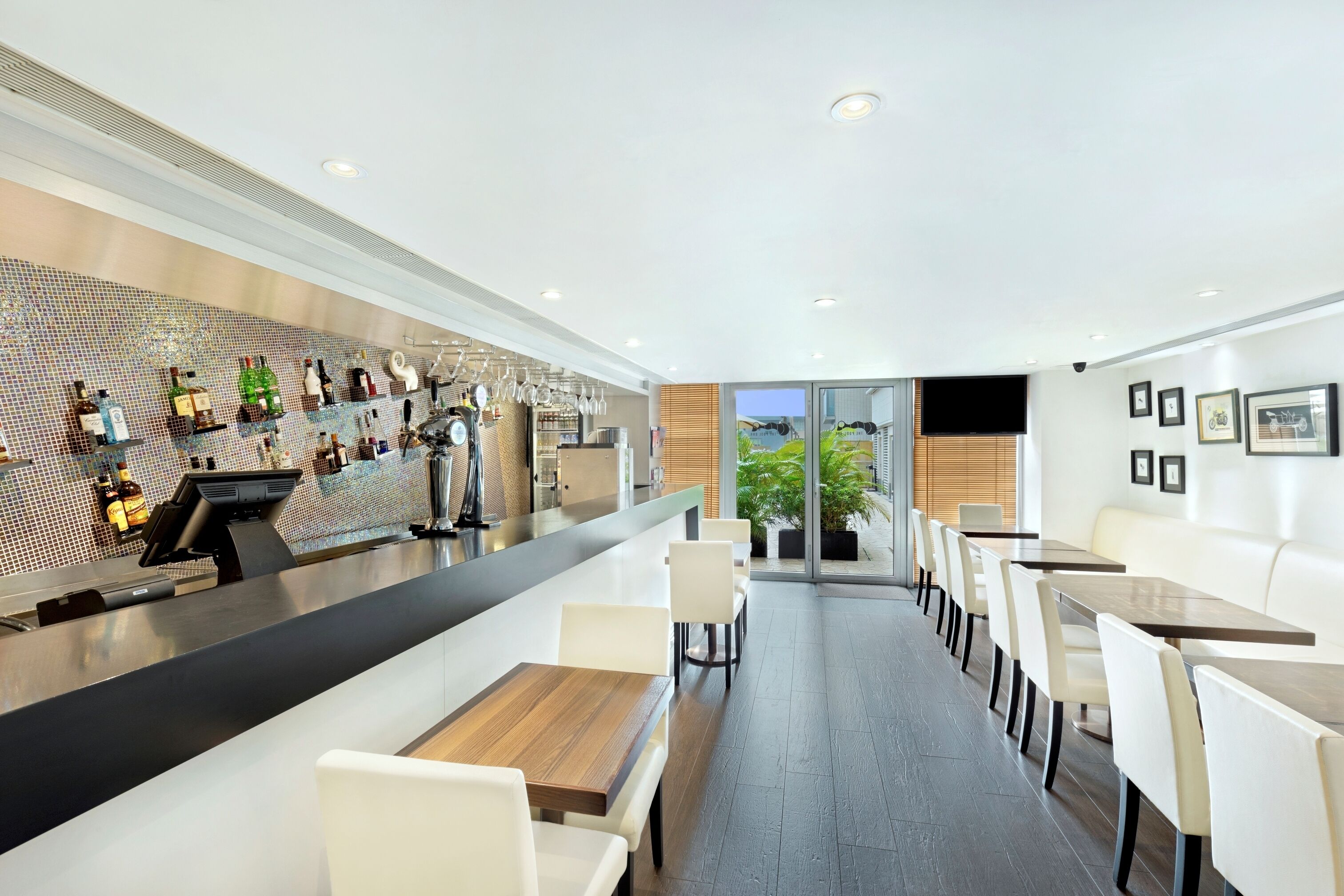 A modern bar area with a counter, seating, and a view of the outdoors.