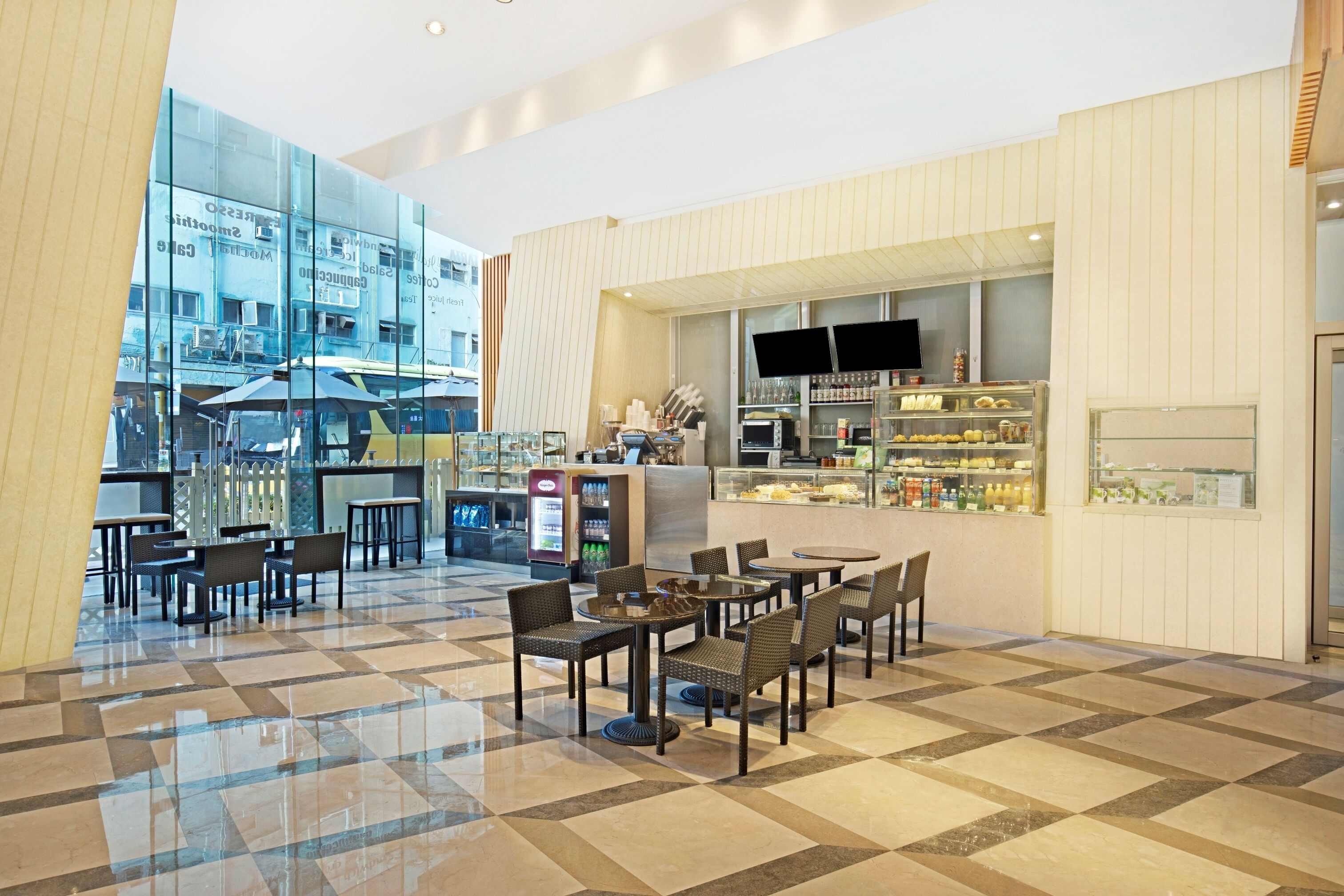 En modern hotellobby med ett rutmönstrat golv, en sittgrupp och ett område där mat och dryck exponeras.